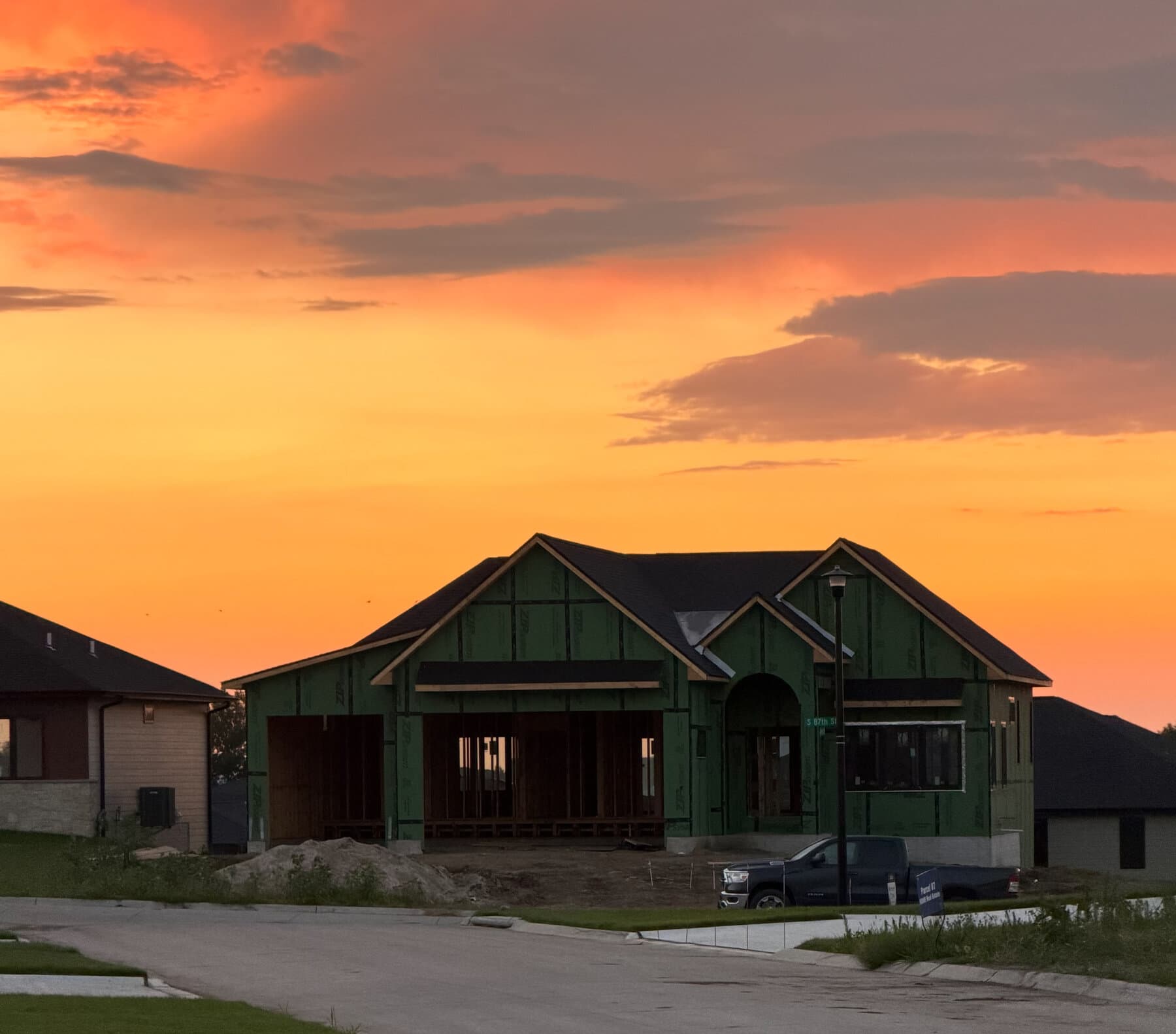 Custom home exterior sheathed and roofed at sunset